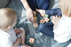 Kinder bauen gemeinsam mit Holzbausteinen einen Turm auf dem Boden