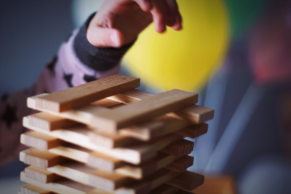 Kind und Erwachsener bauen mit schmalen Holzplättchen eine Konstruktion