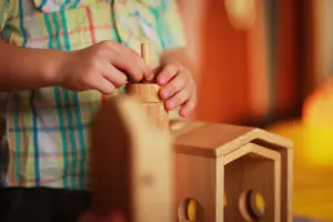 Hände beim Spielen mit Holzbausteinen: sichere Verarbeitung und altersgerechtes Spielzeug